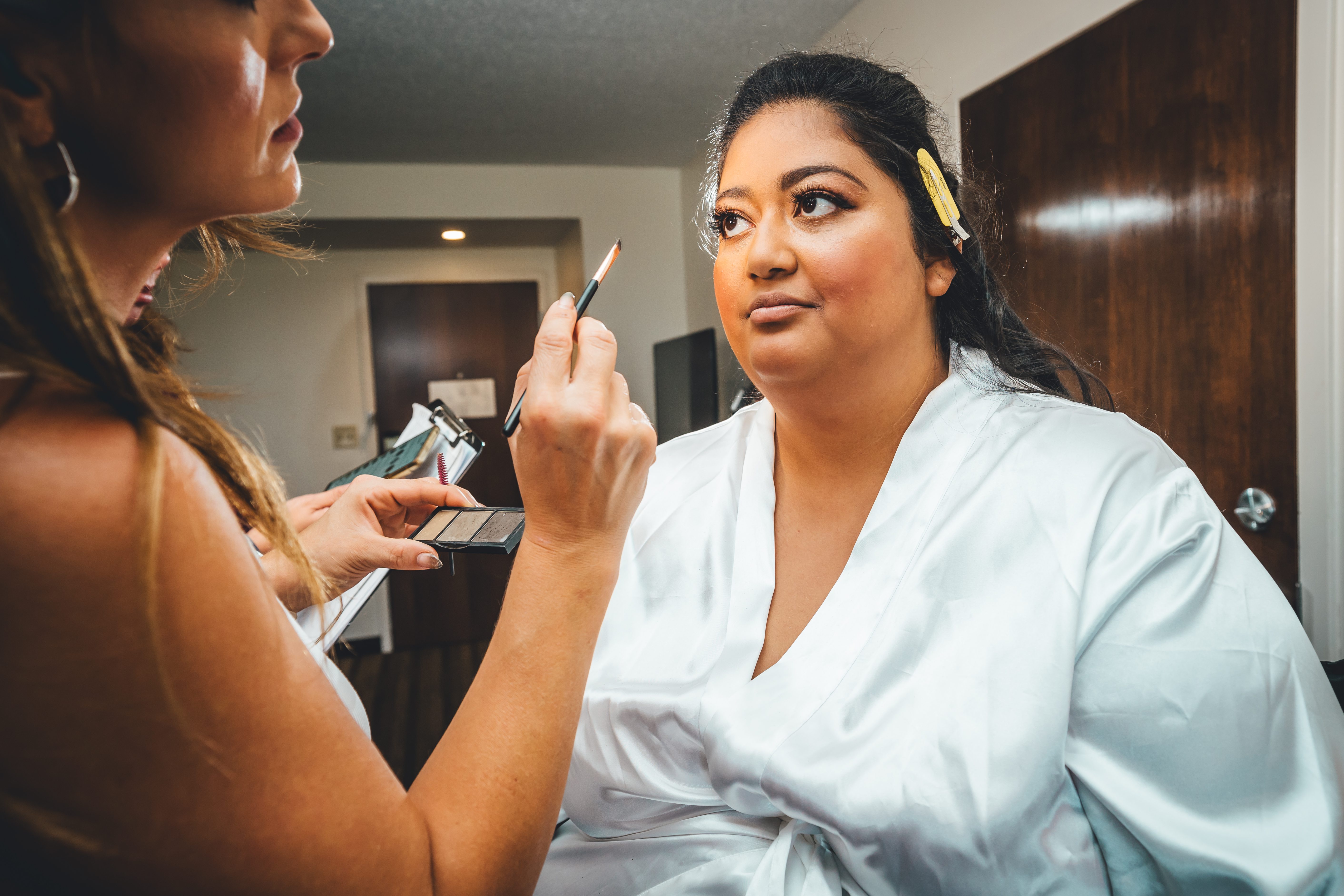 A makeup artist works on the bride while she gets into character for the day