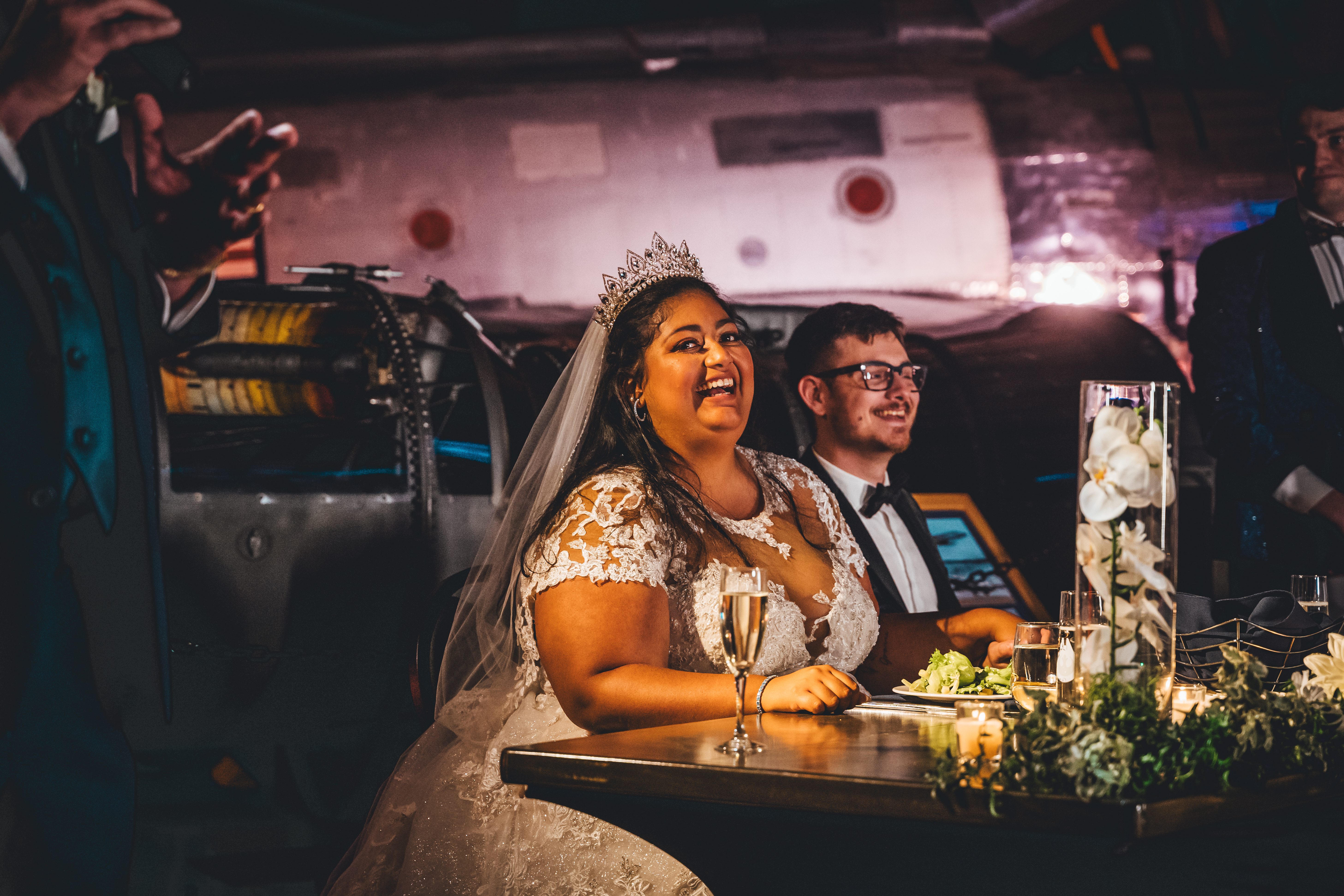A couple laughs together at their sweetheart table