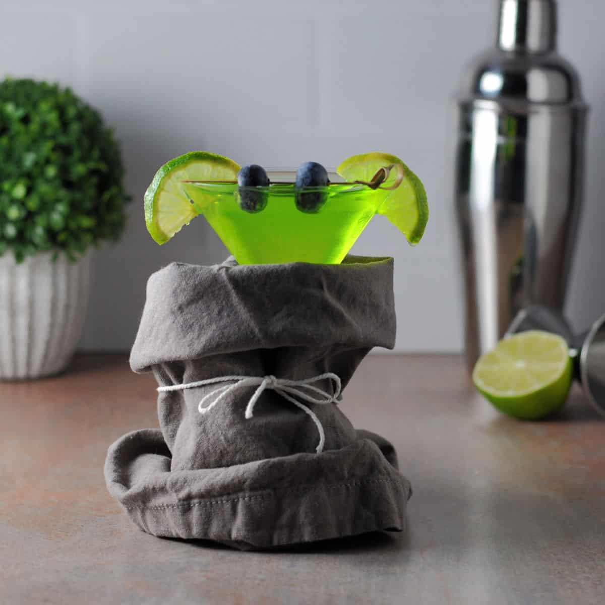 A green Baby Yoda cocktail with lime wedge ears and blueberry eyes