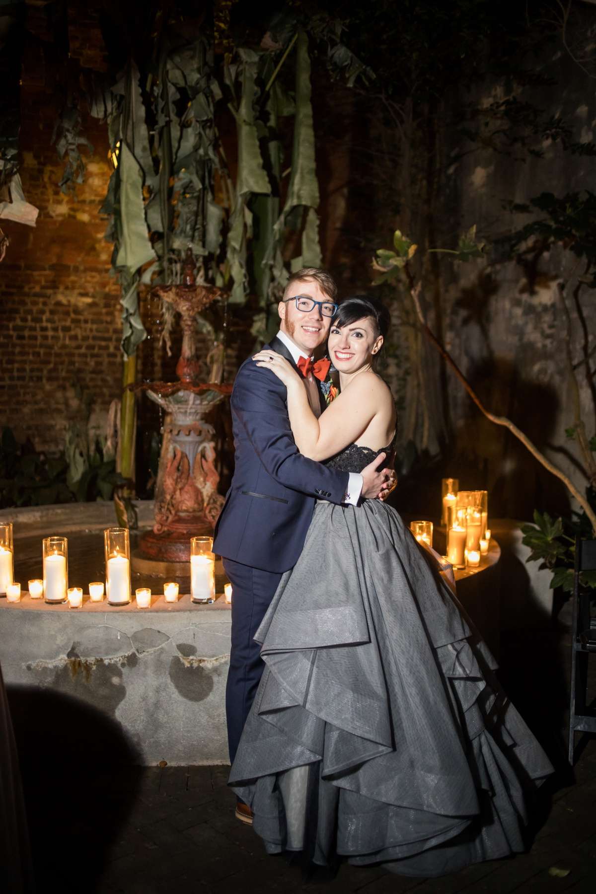 A couple embraces beside a candle-lit courtyard fountain at their Star Wars wedding