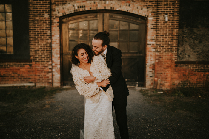 A couple embraces in front of Basilica Hudson's brick facade and arched doors