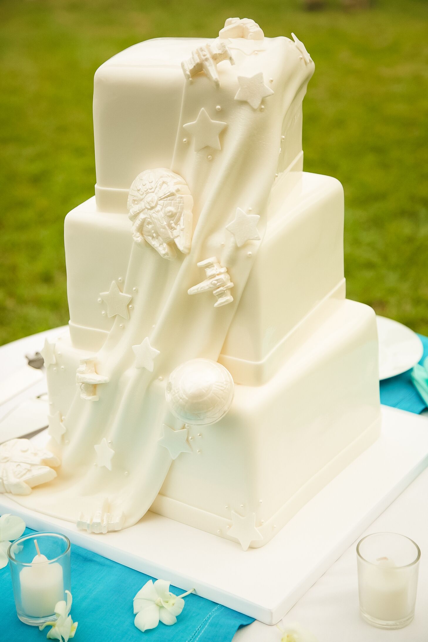 Ivory tiered wedding cake with a fondant drape and Star Wars ships peeking through