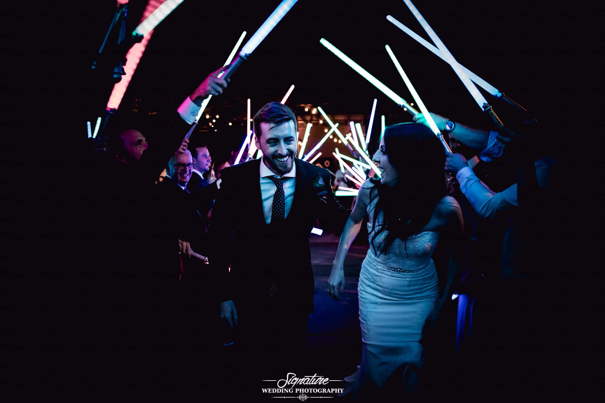 Wedding exit through a lightsaber tunnel by Signature Wedding Photography