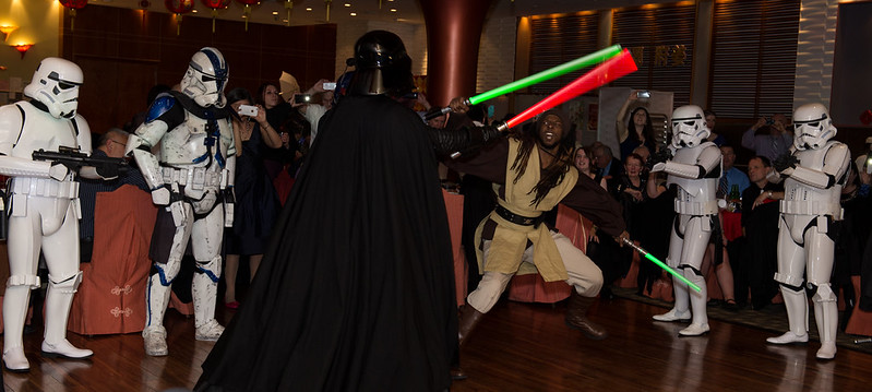 Darth Vader duels a Jedi on the reception dance floor flanked by stormtroopers