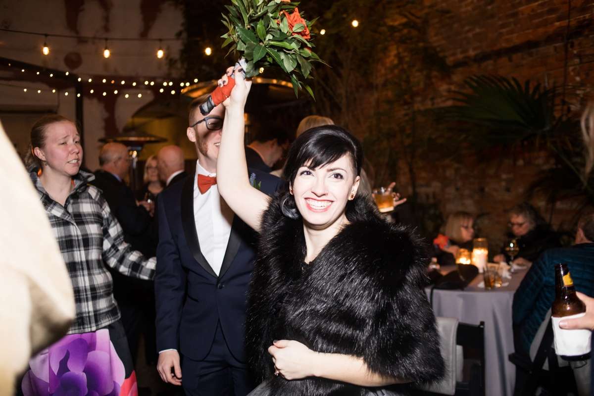 A bride tosses a bouquet built on a lightsaber hilt